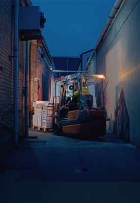 Un callejón oscuro con un montacargas que carga entregas a un camión